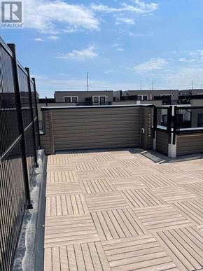 Toronto (Rouge) townhouse for rent - A wooden deck with a black railing and a building in the background.