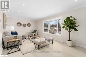 Orillia apartment for rent - A well-lit living room with a grey sofa, a wooden coffee table, and a large window with a view of the outdoors.