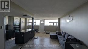 St. Catharines (Glendale/Glenridge) condo for rent - A spacious living room with a black sofa and a large window.