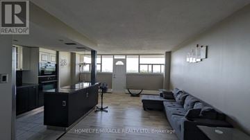 St. Catharines (Glendale/Glenridge) condo for rent - A spacious living room with a black sofa and a large window.