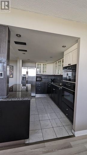 St. Catharines (Glendale/Glenridge) condo for rent - A kitchen with black cabinets and a marble countertop.