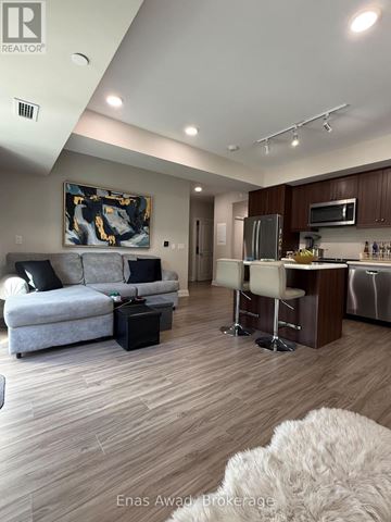 St. Catharines (Oakdale) condo for rent - A modern living room with a grey couch and a painting on the wall.