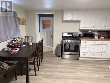 South-West Oxford (Brownsville) apartment for rent - A kitchen with a table and chairs in the foreground and a microwave on the counter.