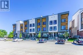 St. Catharines (E. Chester) townhouse for rent - A multi-story building with a parking lot in front.