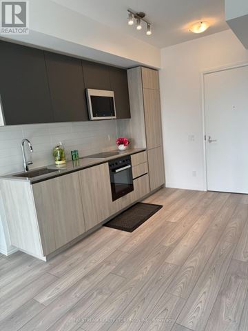 Toronto (Waterfront Communities) condo for rent - A modern kitchen with wooden cabinets and a white countertop.