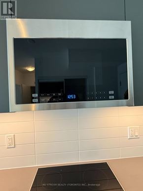 Toronto (Waterfront Communities) condo for rent - A modern kitchen with a digital clock on the wall.