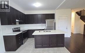 Innisfil apartment for rent - A kitchen with dark wood cabinets and a white countertop.