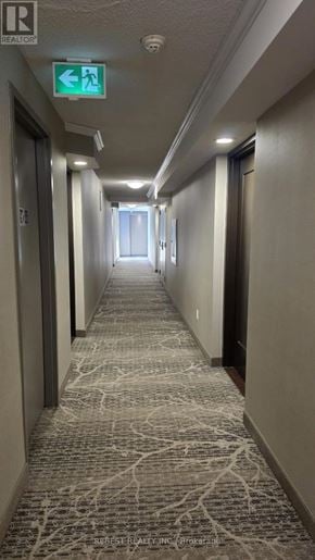 Mississauga (Hurontario) condo for rent - A hallway with a green exit sign above it.
