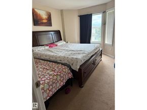 Edmonton townhouse for rent - A bedroom with a bed, nightstand, and window.