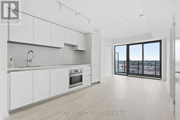 Toronto (Thorncliffe Park) condo for rent - A modern kitchen with white cabinets and a view of the city.