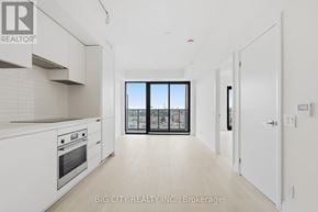 Toronto (Thorncliffe Park) condo for rent - A white kitchen with a view of the city through the window.