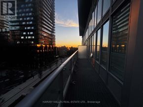 Toronto (Mount Pleasant West) condo for rent - A balcony overlooks a city street at sunset.