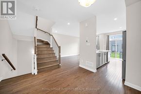 Ottawa townhouse for rent - A spacious room with wooden floors and a staircase with a wooden handrail.