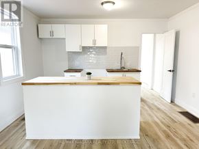 St. Catharines (Western Hill) apartment for rent - A kitchen with white cabinets and a wooden island.