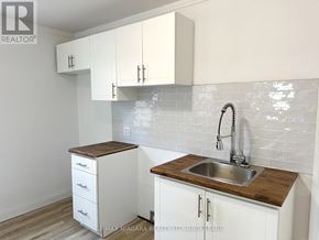St. Catharines (Western Hill) apartment for rent - A kitchen with white cabinets and a wooden countertop.