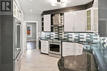 Kitchener condo for rent - A modern kitchen with a refrigerator on the left and a stove top oven in the center.