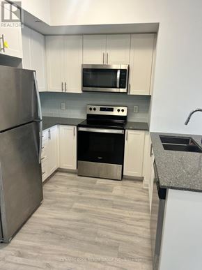 Markham (Greensborough) condo for rent - A kitchen with a stainless steel refrigerator, microwave, oven, and sink.