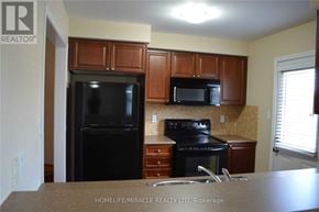 Milton (Co Coates) townhouse for rent - A kitchen with black appliances and brown cabinets.