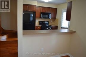 Milton (Co Coates) townhouse for rent - A kitchen with a black stove top oven and black microwave.