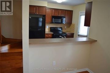 Milton (Co Coates) townhouse for rent - A kitchen with a black stove top oven and black microwave.