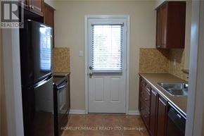 Milton (Co Coates) townhouse for rent - A kitchen with a black refrigerator and brown cabinets.