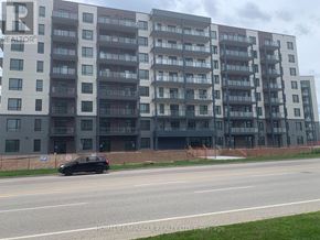 Guelph (Willow West/Sugarbush/West Acres) condo for rent - A black car is driving on a road in front of a large apartment building.