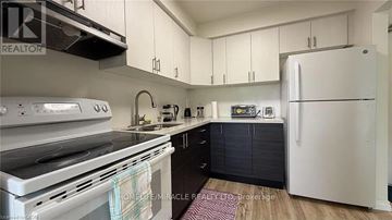 Kitchener multi-family for rent - A kitchen with white appliances and cabinets.