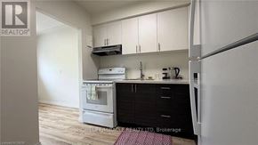 Kitchener multi-family for rent - A kitchen with a refrigerator, oven, and cabinets.
