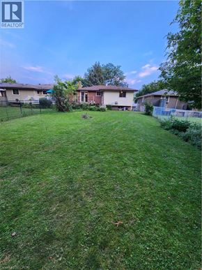 Waterloo apartment for rent - A backyard with a well-maintained lawn and a house in the background.