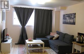 Vaughan (Patterson) apartment for rent - A living room with a grey couch, a coffee table, and a television.