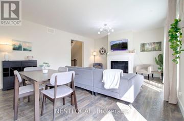 Blue Mountains apartment for rent - A living room with a grey couch, a wooden table and chairs, a fireplace, and a painting on the wall.