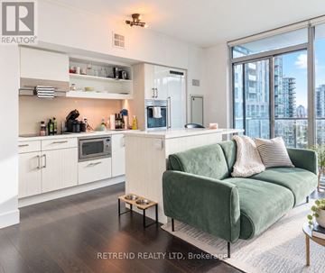 Toronto (Moss Park) condo for rent - A modern kitchen with a green couch in the living room.
