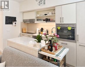 Toronto (Moss Park) condo for rent - A modern kitchen with a grey couch and a wooden table with a tray of food and flowers on it.