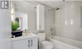 Toronto (Moss Park) condo for rent - A white bathroom with a tub, toilet, and sink.