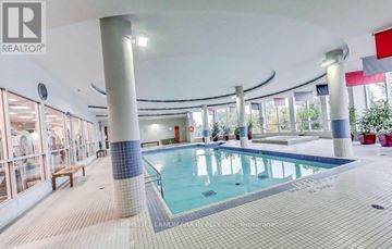 Toronto (Bayview Village) condo for rent - A large indoor swimming pool with a tiled edge and a bench to the side.
