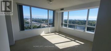 Toronto (Bayview Village) condo for rent - A large, empty room with a view of the cityscape outside the windows.