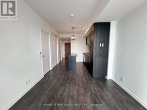 Vaughan (Vaughan Corporate Centre) condo for rent - A spacious room with wooden flooring and a kitchen area with dark cabinets.