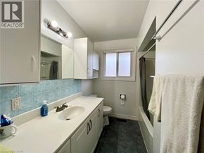 Waterloo apartment for rent - A bathroom with a sink, mirror, toilet, and a window.