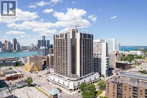 Windsor condo for rent - A cityscape with a large building in the foreground and a body of water in the background.