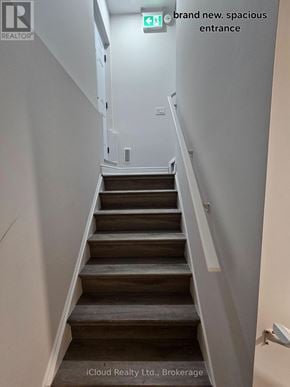Clarington (Bowmanville) apartment for rent - A staircase with a green exit sign above it.