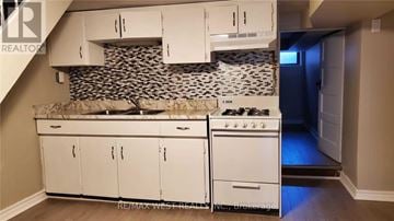 Toronto (Dovercourt-Wallace Emerson-Junction) apartment for rent - A kitchen with white cabinets and a black and white tiled backsplash.
