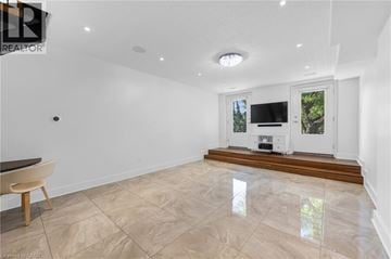 Hamilton apartment for rent - A spacious living room with a television and a window overlooking a tree.