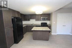 Kitchener condo for rent - A kitchen with a black fridge and microwave, brown cabinets, and a marble island.