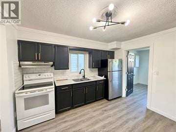 Windsor apartment for rent - A kitchen with black cabinets and a white stove top oven.