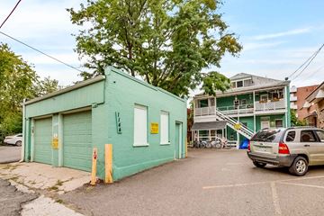 Denver apartment for rent - A green building with a garage door and a sign on the door.