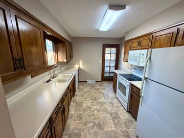 Fremont apartment for rent - A kitchen with a white refrigerator, brown cabinets, and a tiled floor.