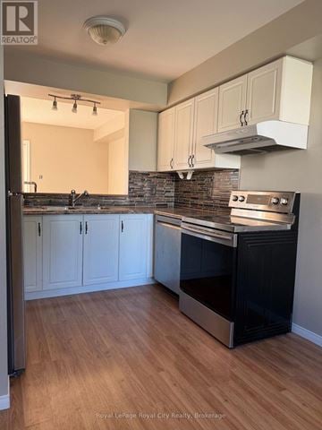Guelph (Downtown) townhouse for rent - A kitchen with a black oven and wooden floors.