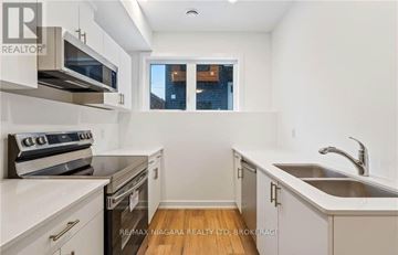 Welland (N. Welland) townhouse for rent - A kitchen with white cabinets and a stove top oven.