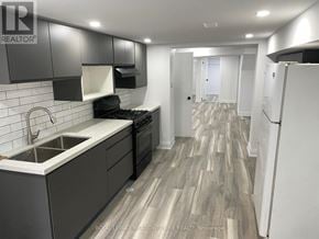 Toronto (Little Portugal) duplex for rent - A modern kitchen with dark wood floors and white appliances.