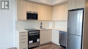 Milton (Tm Timberlea) condo for rent - A kitchen with a refrigerator, oven, and microwave.